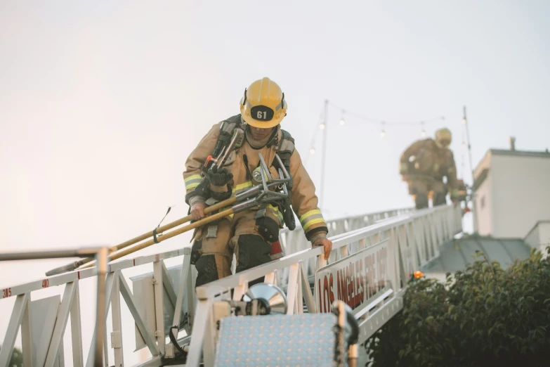 two fire fighters are on the ladder near some chairs