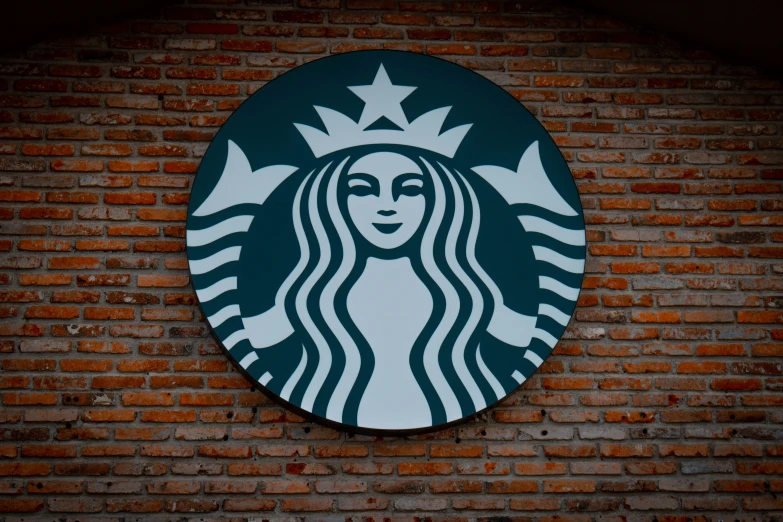 a starbucks logo on a wall behind a brick background