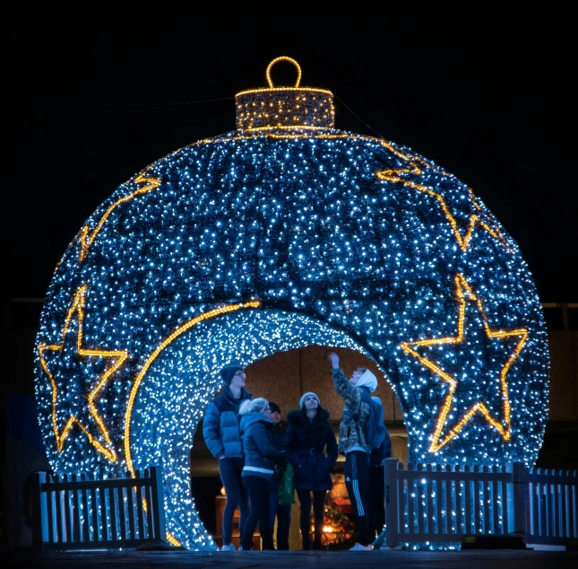 a group of people standing next to each other in front of a lit up ball