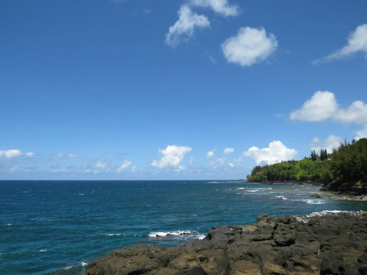 rocks out in the ocean and clouds and blue sky