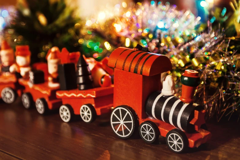 a small toy train traveling next to a christmas tree