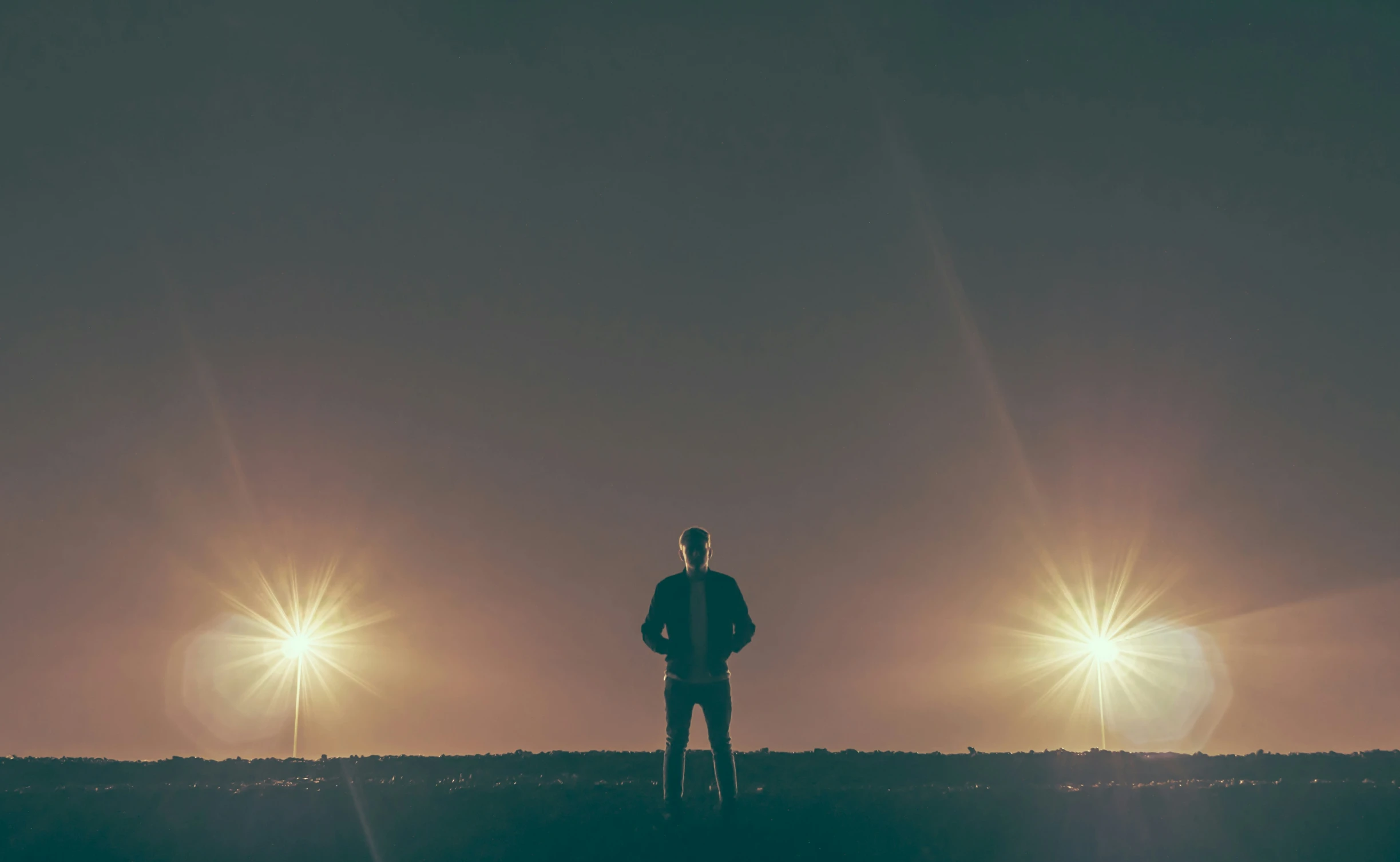 a silhouette of a man in front of three bright lights