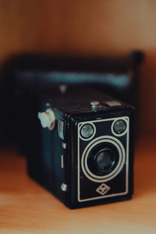 an old camera is on the table next to it's strap