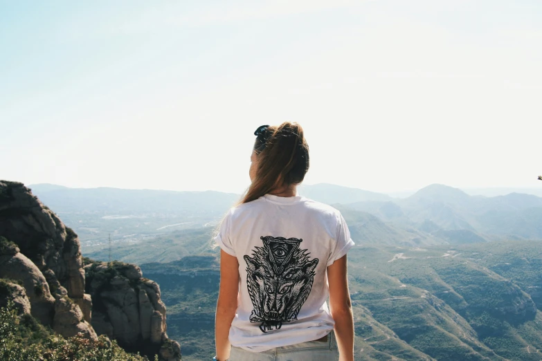 a woman is looking down at the mountains