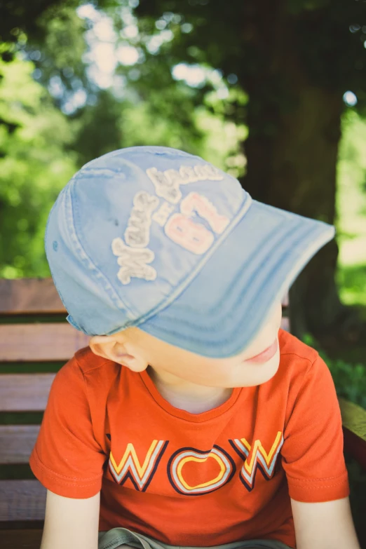 a little  sitting on a wooden park bench