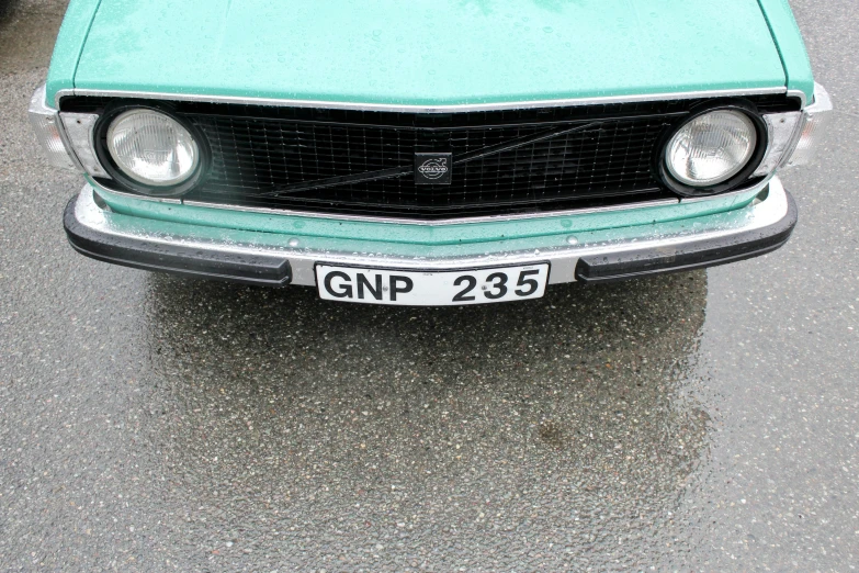 an older car is sitting on the wet pavement