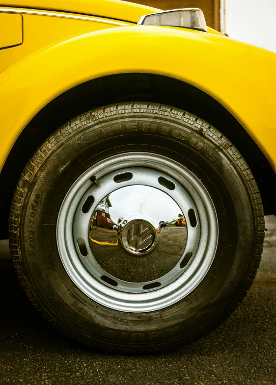 an antique yellow car with chrome spokes and flat tire