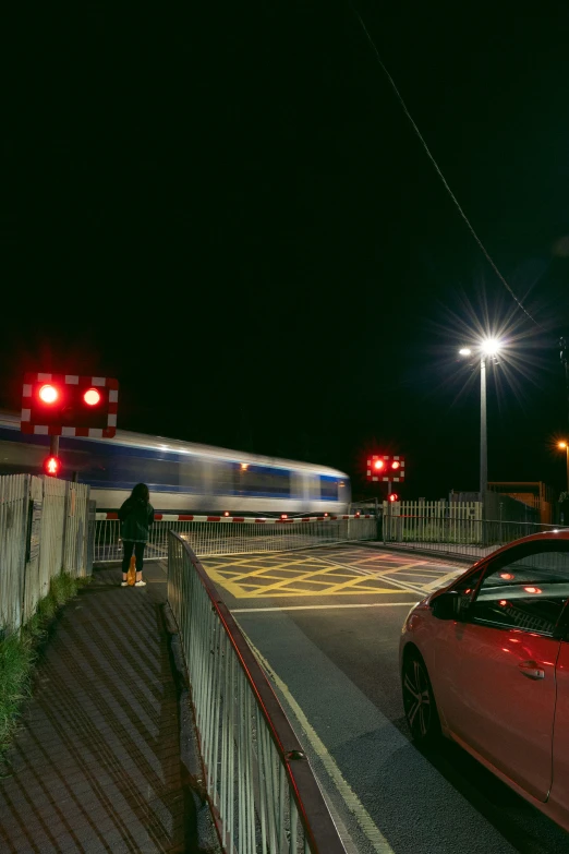 a red car at a railroad crossing, at night