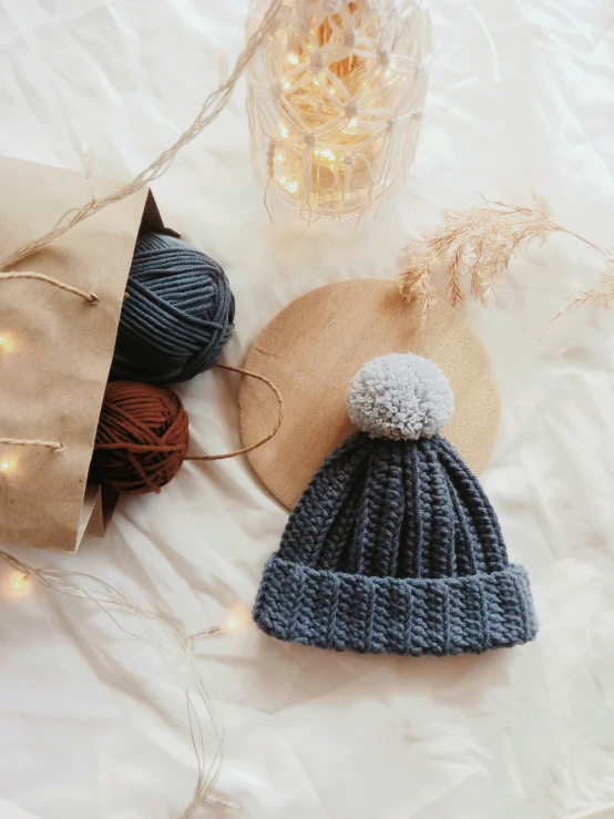 two knitted hats and yarns on a white sheet