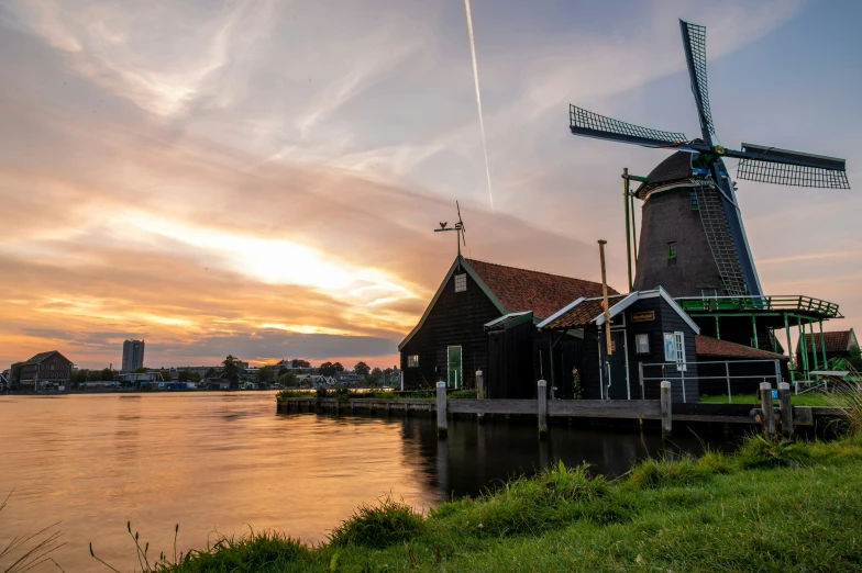 windmills stand in front of a sunset on a river