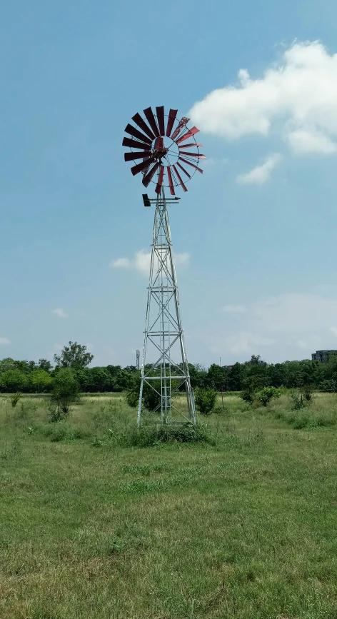 a windmill that is out in the middle of some grass