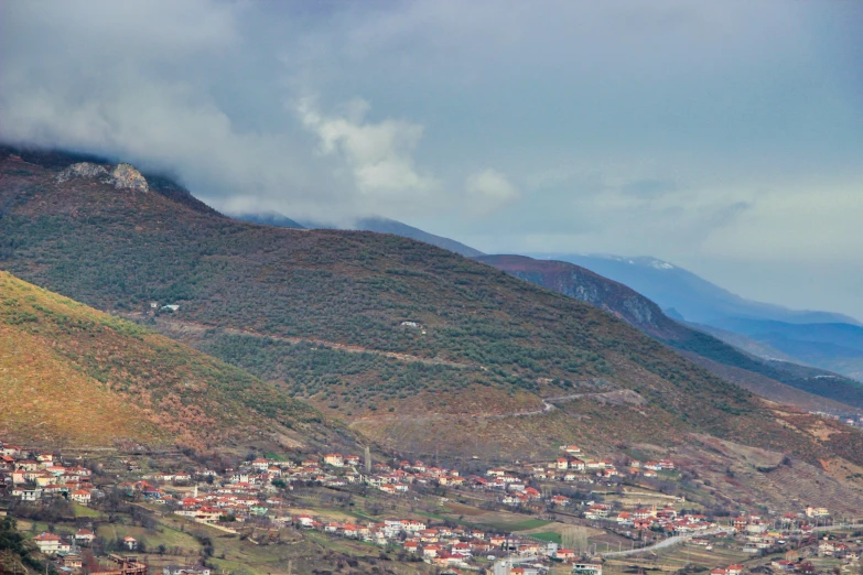 a city in the middle of mountains with hills and buildings below