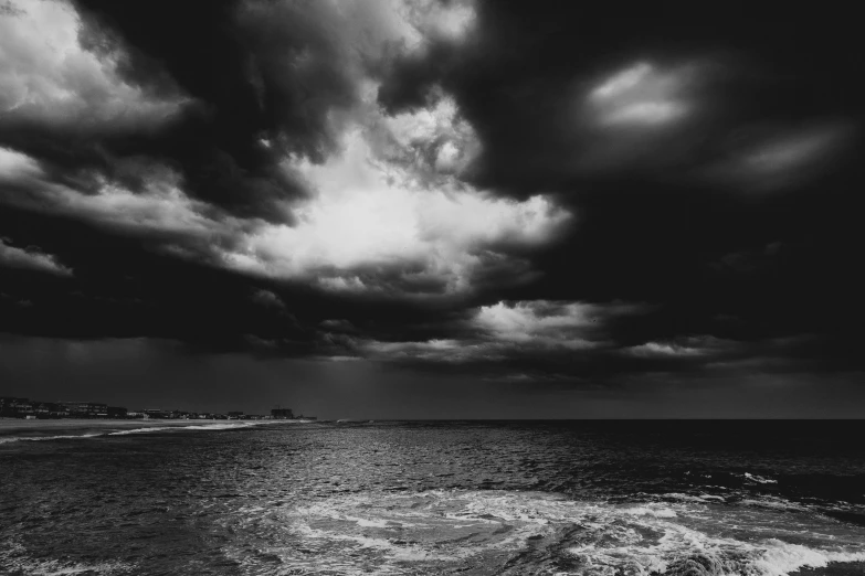 the cloudy skies in black and white are over the ocean