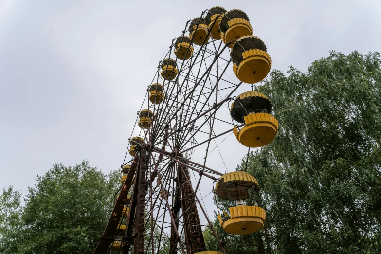 a yellow ferris wheel sitting next to some trees