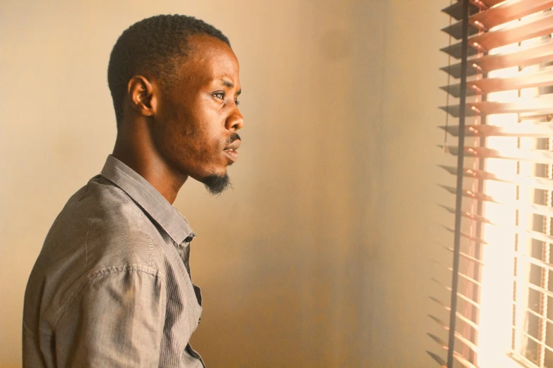 man standing by the window looking out the blinds