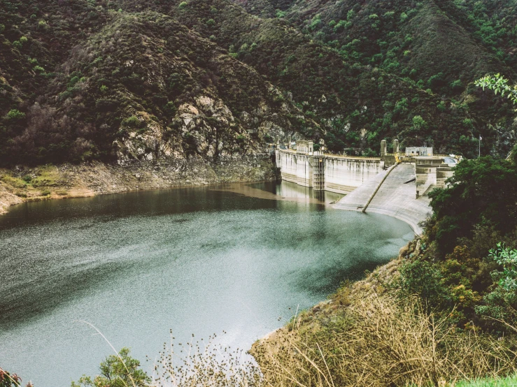 the water in the lake is blue with a small dam at the edge