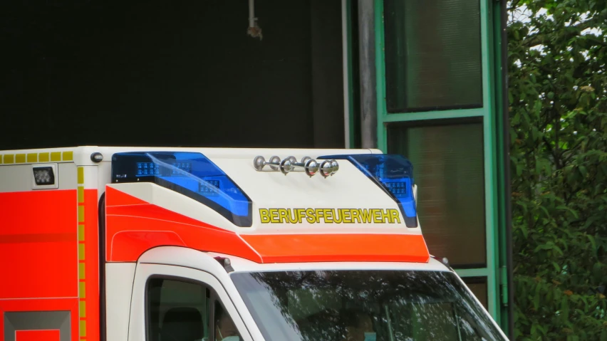 an emergency ambulance parked next to a window in front of trees