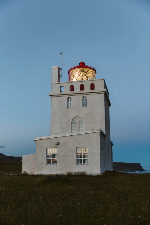 a large lighthouse sits in front of a hill on a sunny day