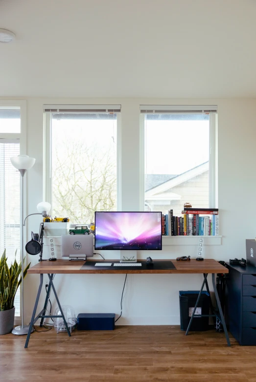 a laptop computer sitting on top of a desk near a window