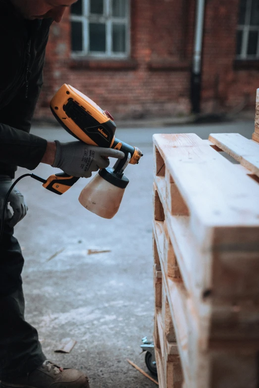 a person is holding a sander and spraying wood