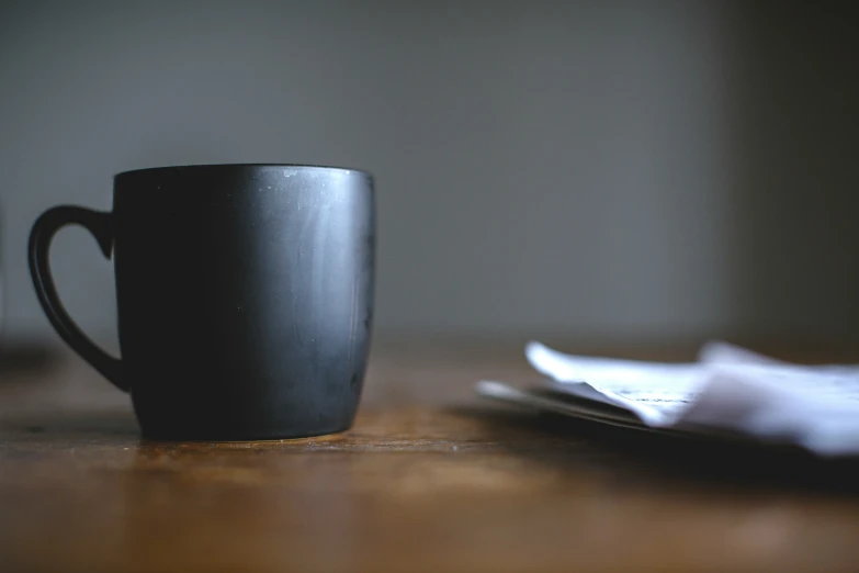 coffee cup and napkin sitting on the table in a darkened room