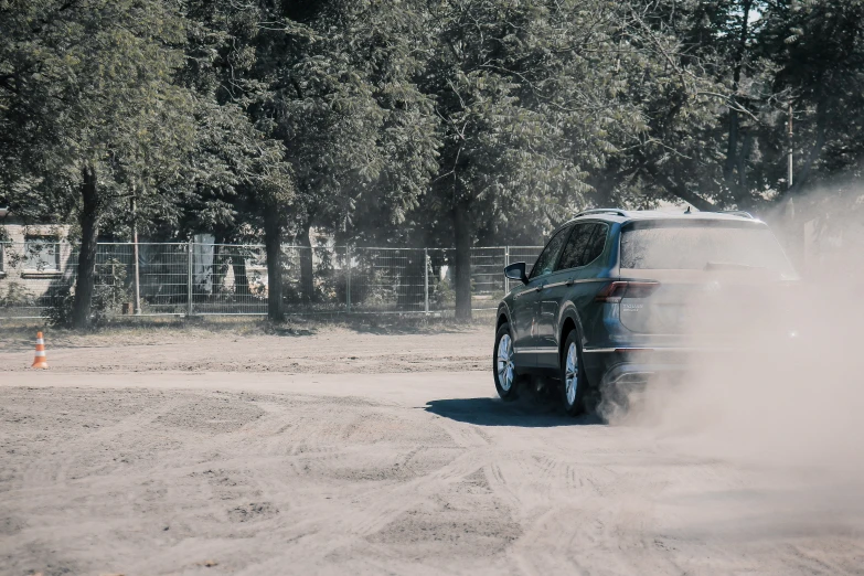 the black car is driving down the dirt road