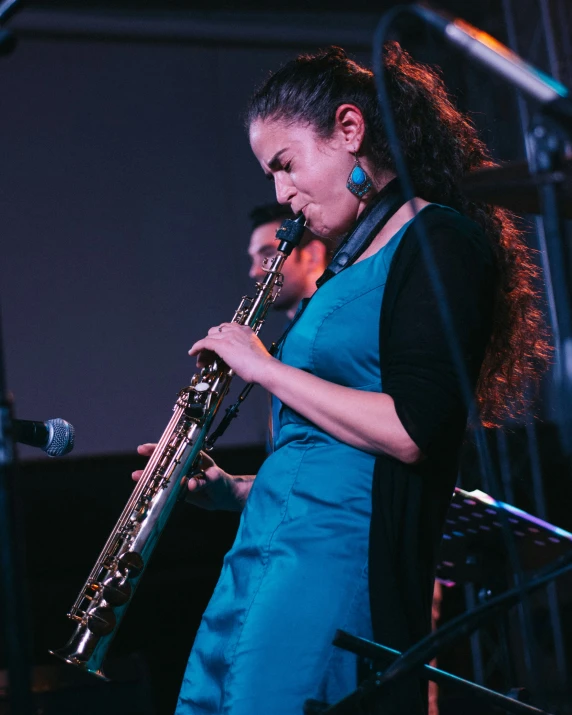 a woman is playing a saxophone and singing