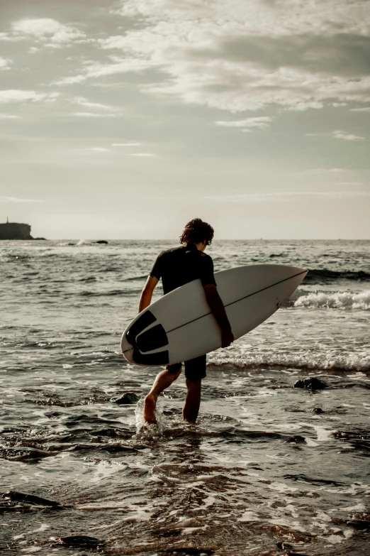 man with white surfboard on ocean beach during day