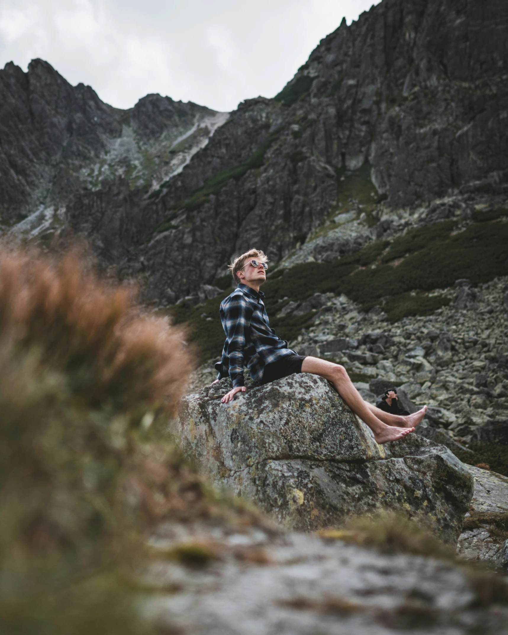 a man is sitting on top of a rock with his legs crossed