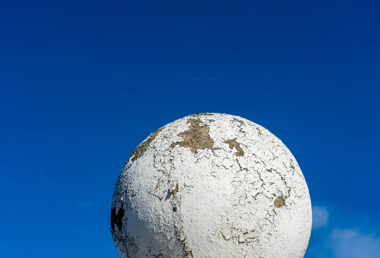 a big stone sculpture sitting on the side of a pole