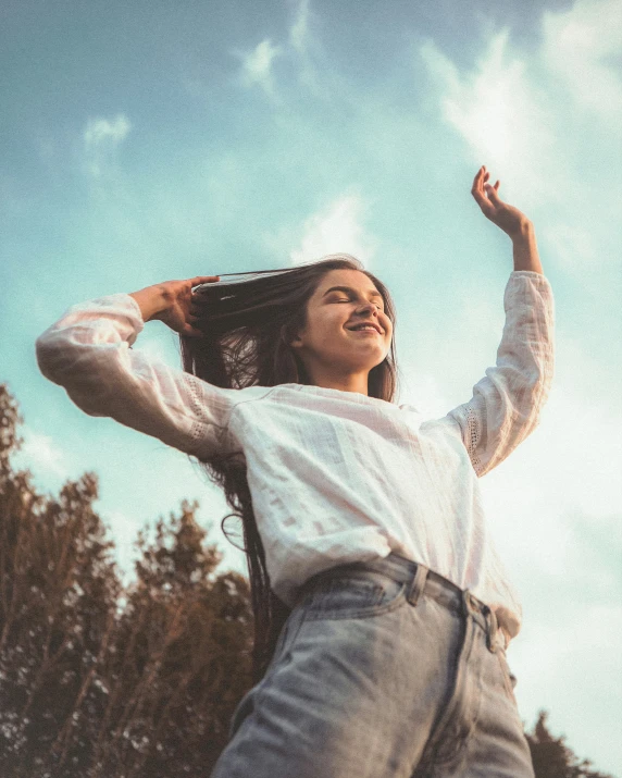 woman with her hair in the wind wearing a white top