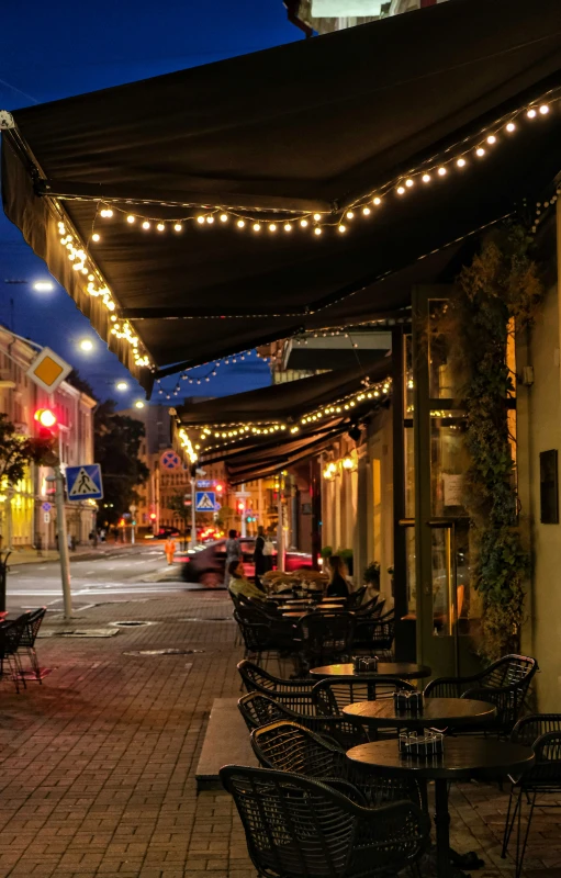 outdoor seating with lights strung up on the side of a street