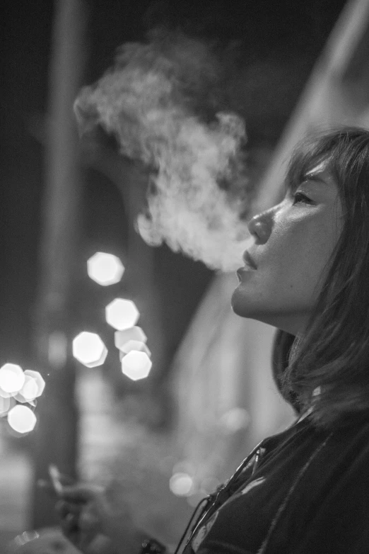 the woman smoking a cigarette stands in the night street