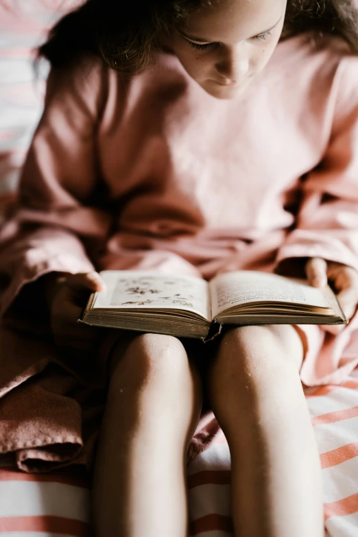 a girl sitting on her bed holding an open book