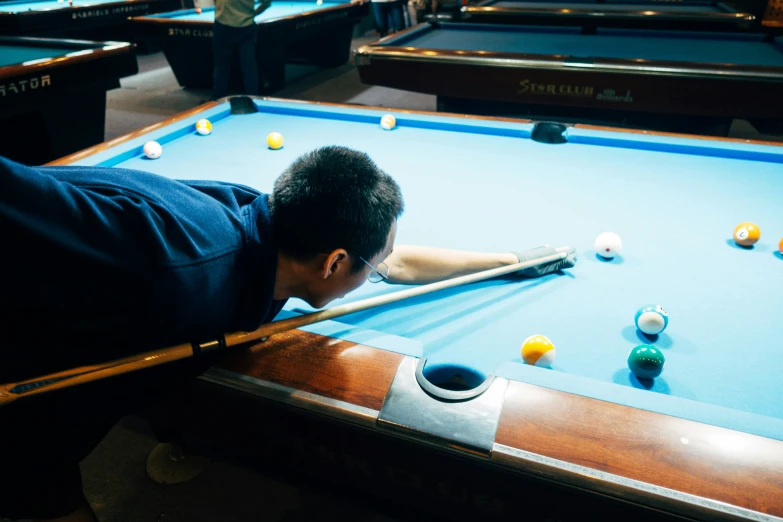 a man leaning over a pool table while playing a game of pool