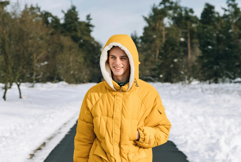 a young man in a yellow jacket standing on a snowy road