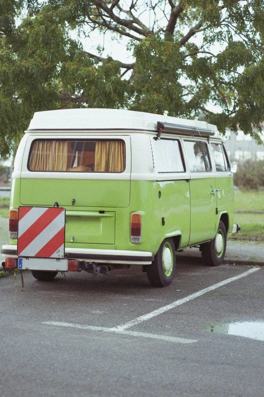 a green and white van sitting in a parking lot