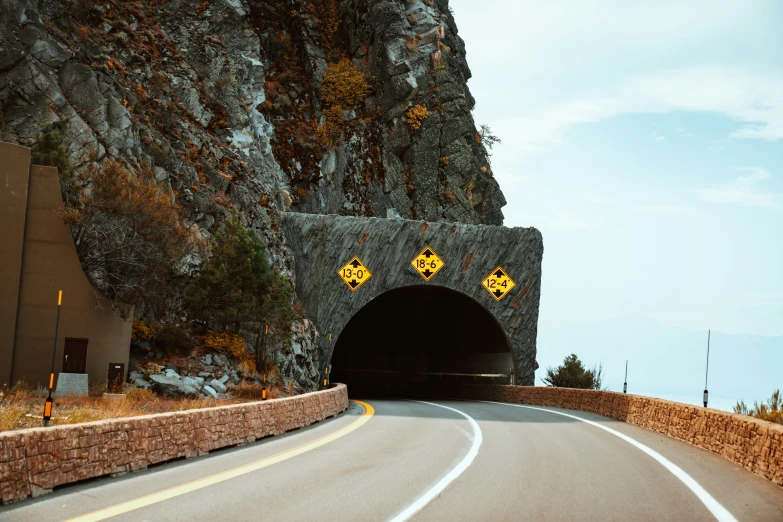 a road going into a large tunnel with yellow traffic signs