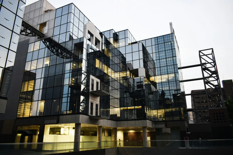 a building with multiple stories and lights reflecting off it's glass front windows