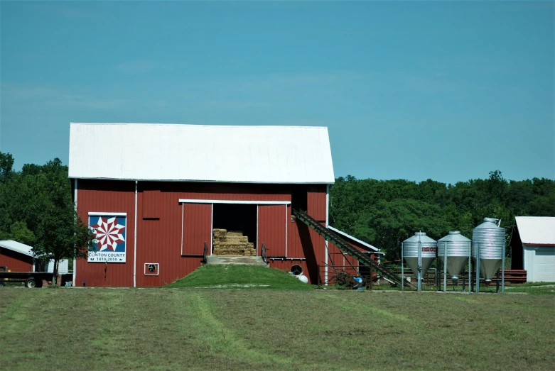 a red barn with several silos and an awning