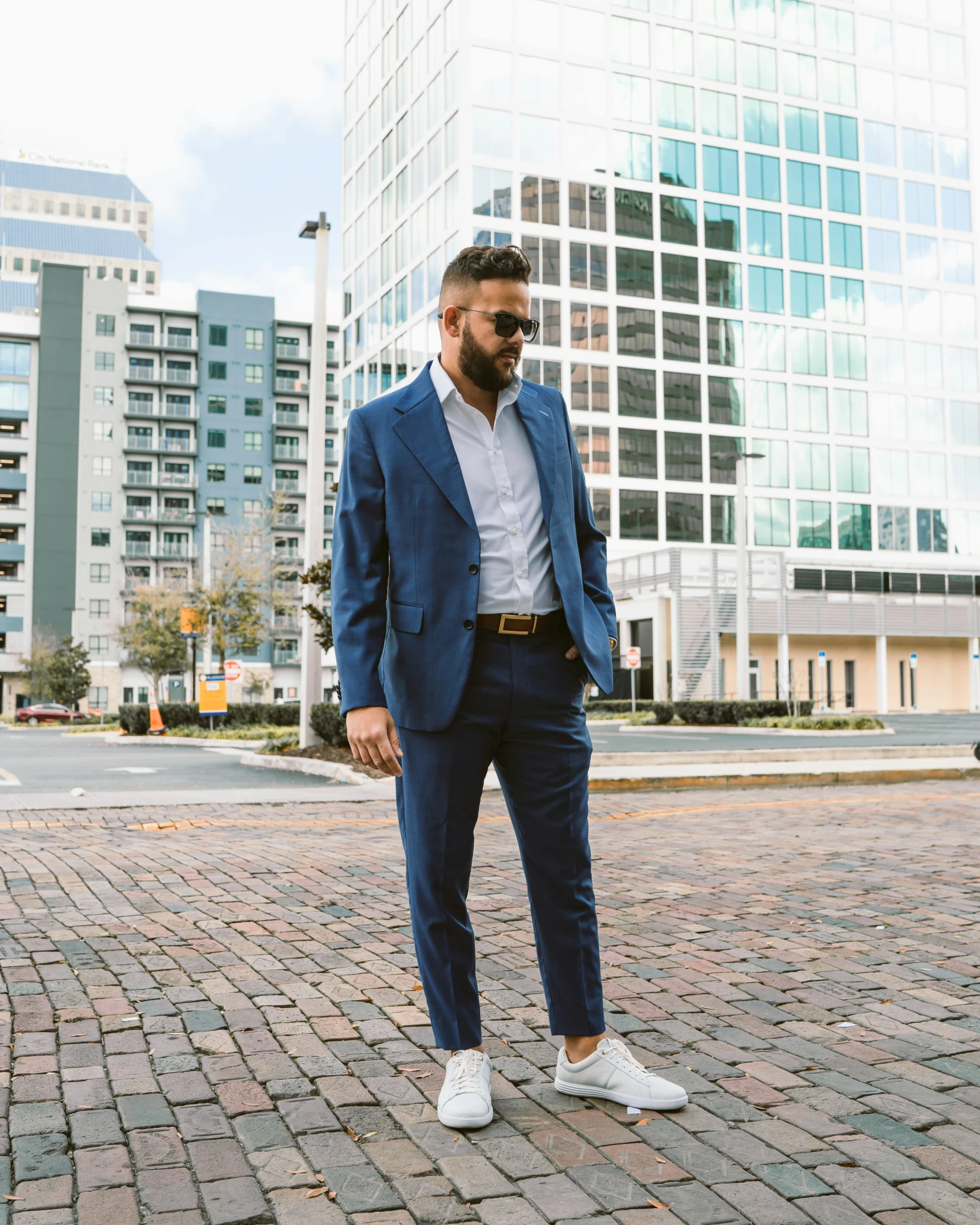 man in business attire with white sneakers on brick sidewalk