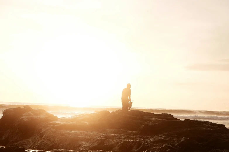 a man on a rocky outcropping looks at the water