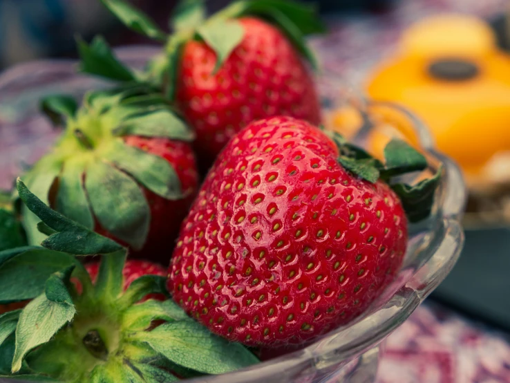 three ripe strawberries on a table next to an ipod