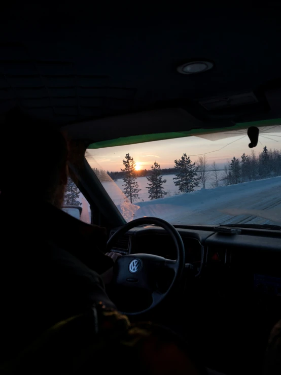 the sun is setting behind a car windshield