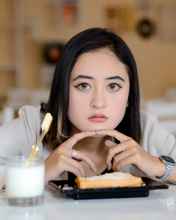 a woman sitting at a table while looking at a sandwich