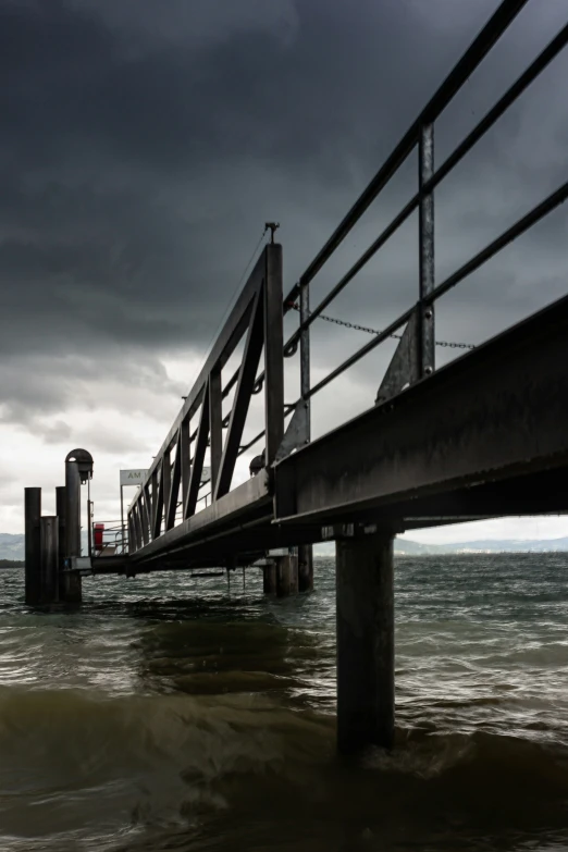 a train tracks on water under a stormy sky