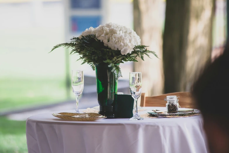 flowers in a vase on top of a white table cloth