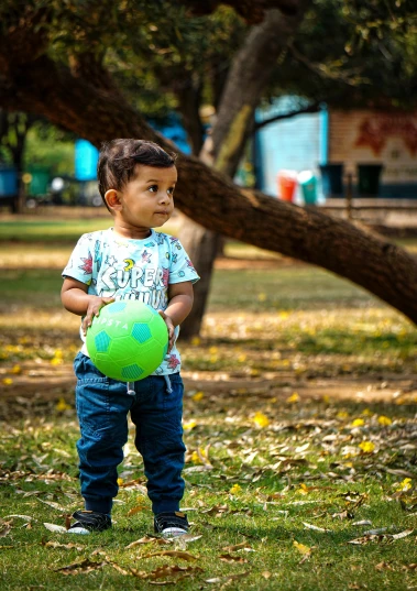 a little boy standing next to a tree