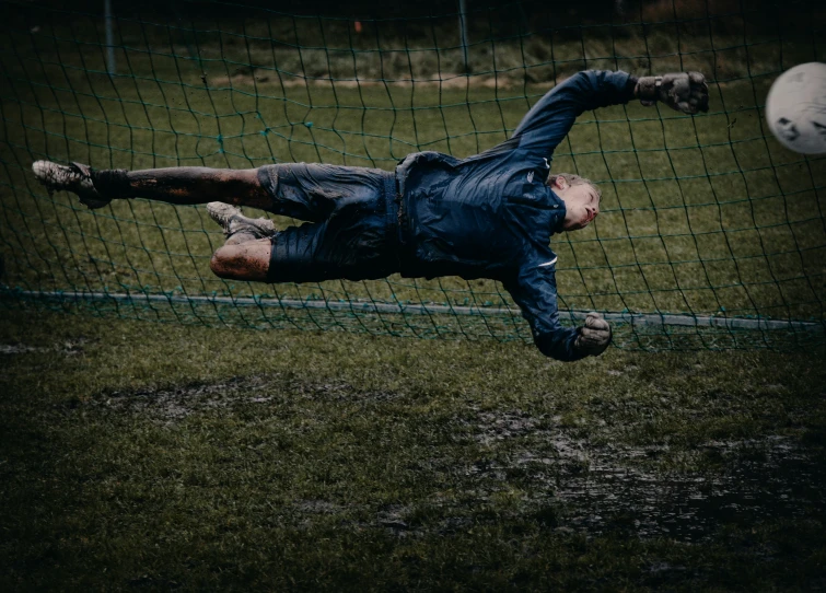 a man laying in a field next to a soccer ball