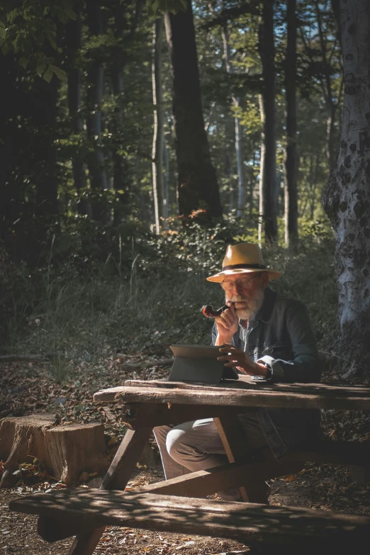 an elderly man sits at a picnic table in the woods